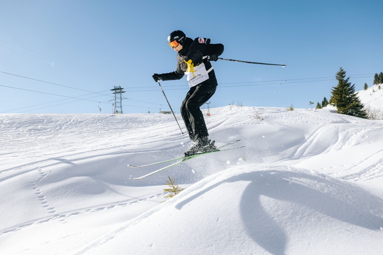 Rennfahrer der Black Academy der Skischule Arosa im Sprung über eine Geländekante