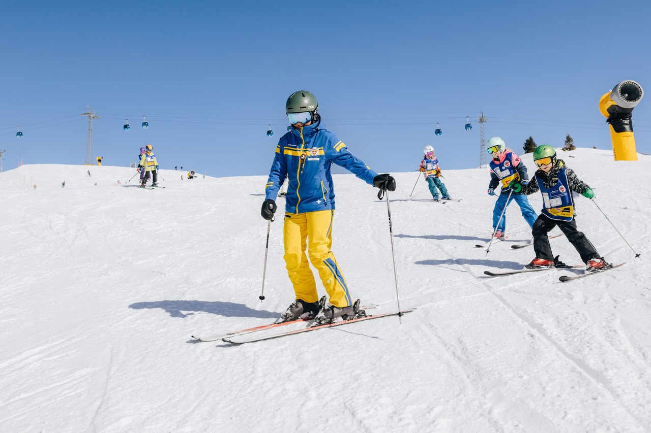 Schneesportlehrer der Skischule Arosa fährt einer Kindergruppe im Blue-Prince-Level voraus