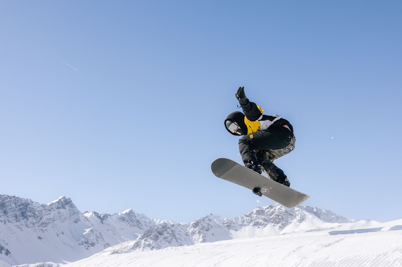 Snowboarderin der Skischule Arosa in der Luft über dem Snowpark Tschuggen
